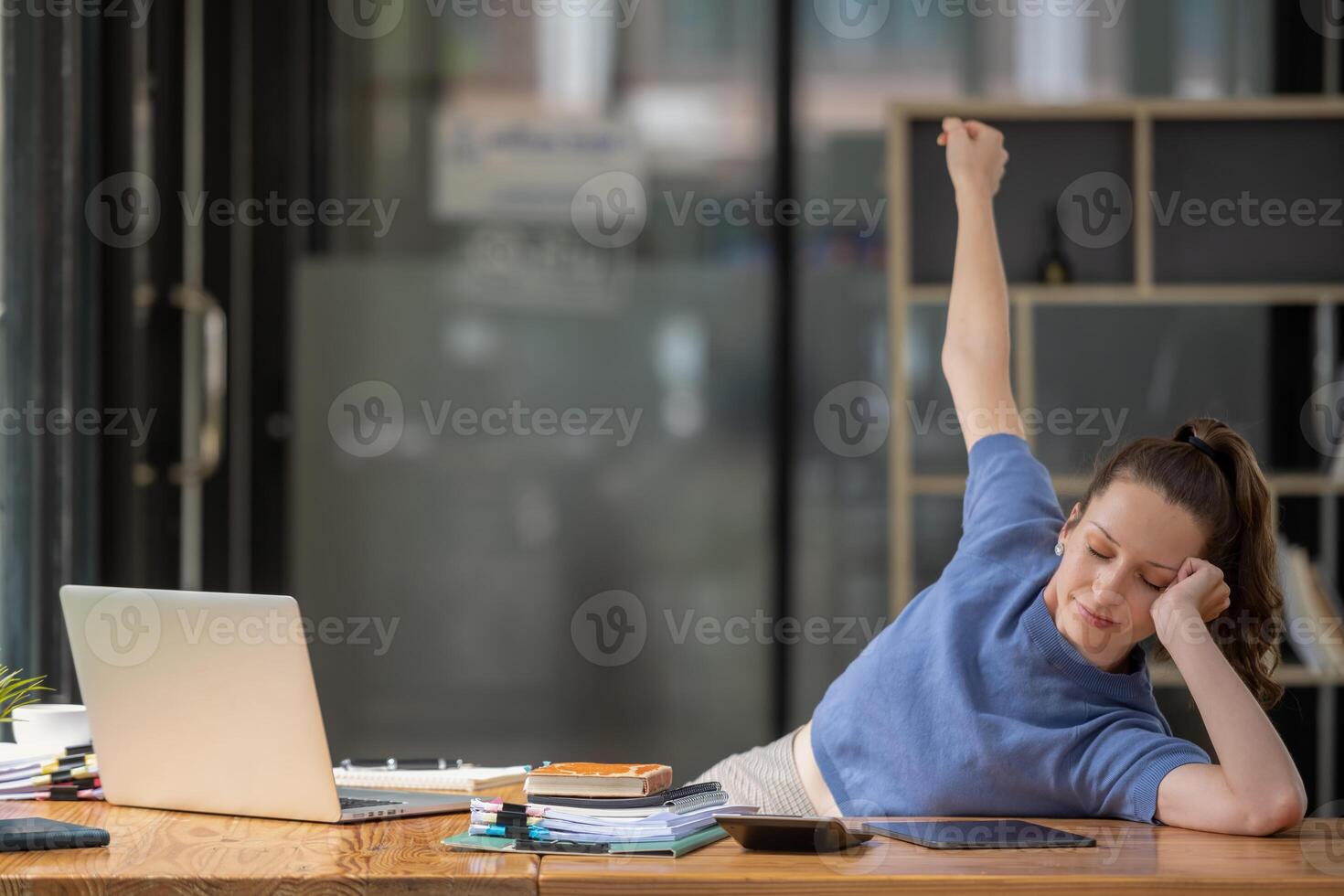 Businesswoman stretching lazy at the desk to relax while working in the office. Feeling stressed and achy from work. photo