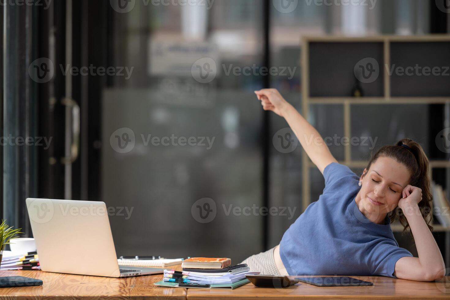 Businesswoman stretching lazy at the desk to relax while working in the office. Feeling stressed and achy from work. photo