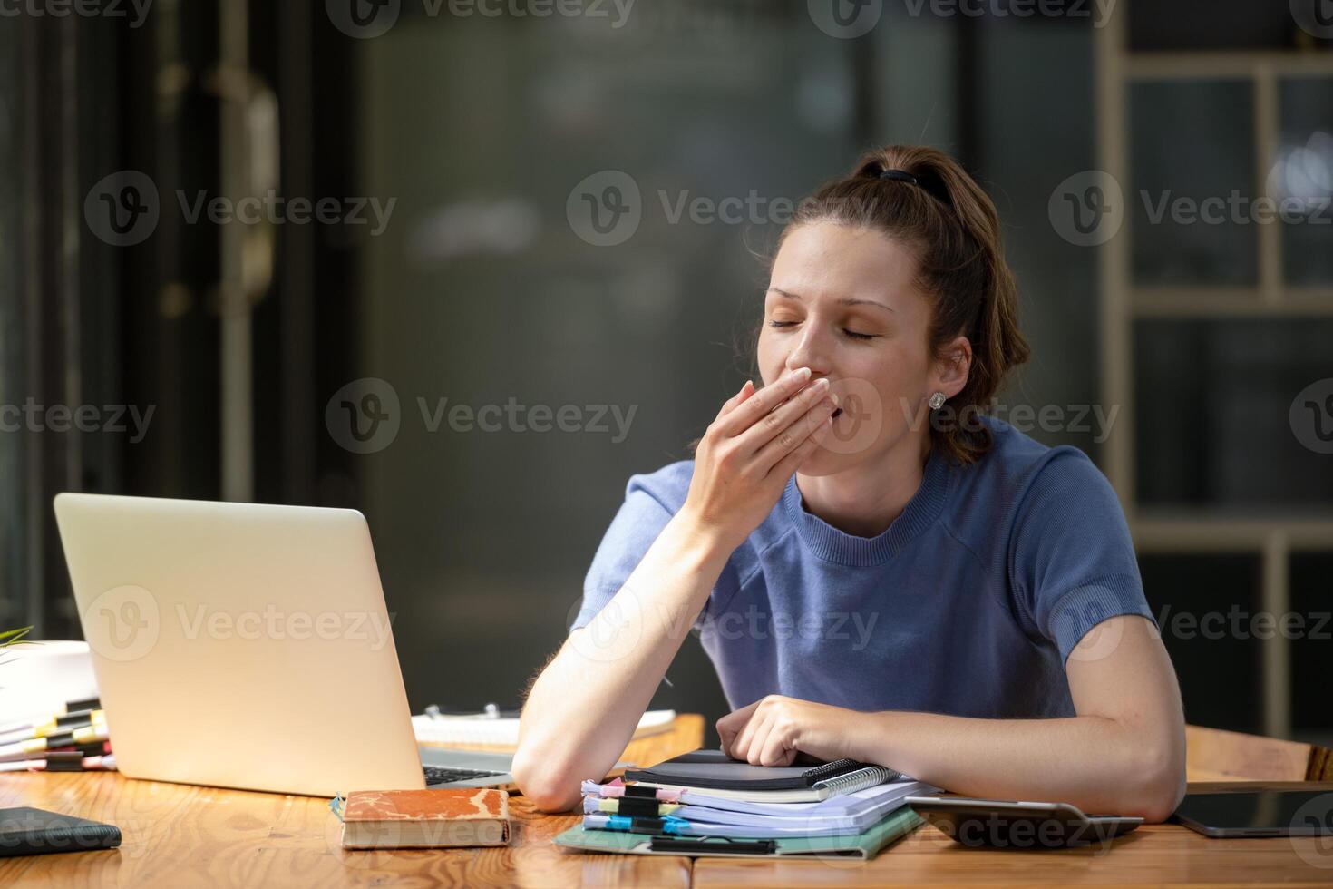 businesswoman yawning while working with a laptop computer. Feeling bored and tired. photo