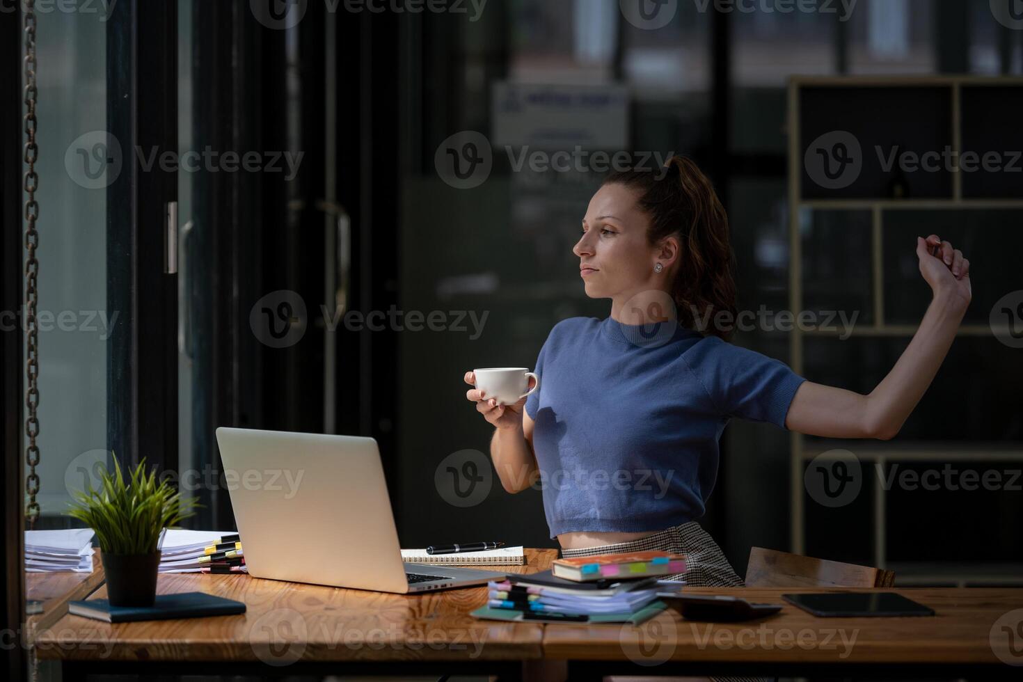 Businesswoman stretching lazy at the desk to relax while take a break from work and enjoy with coffee in the office. Feeling stressed and achy from work. photo