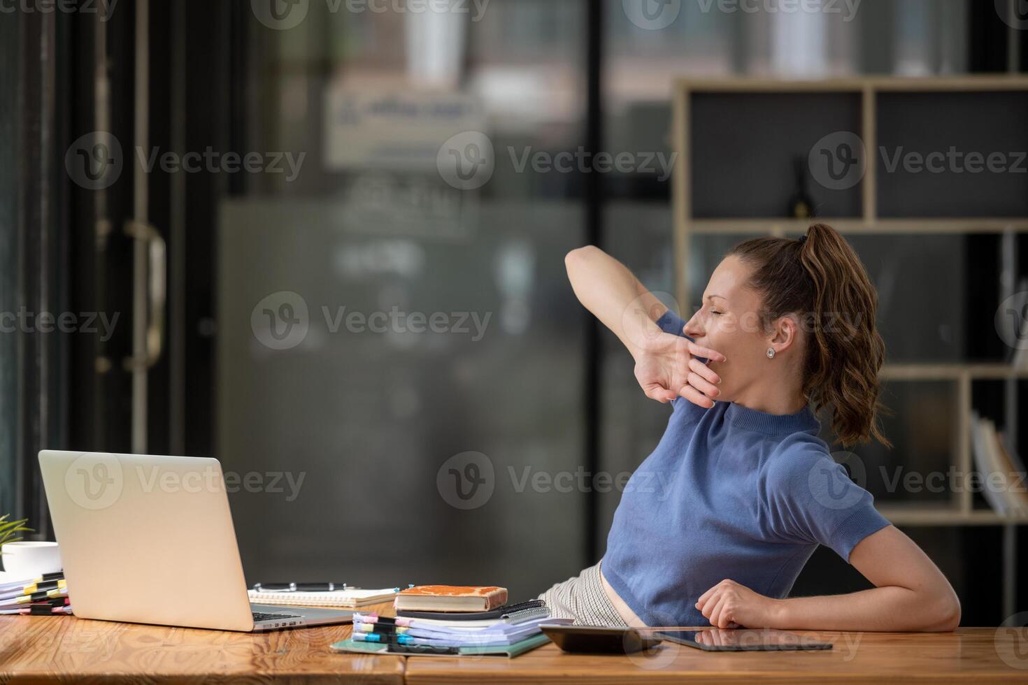 businesswoman yawning and stretching lazy while working with a laptop computer. Feeling bored and tired photo