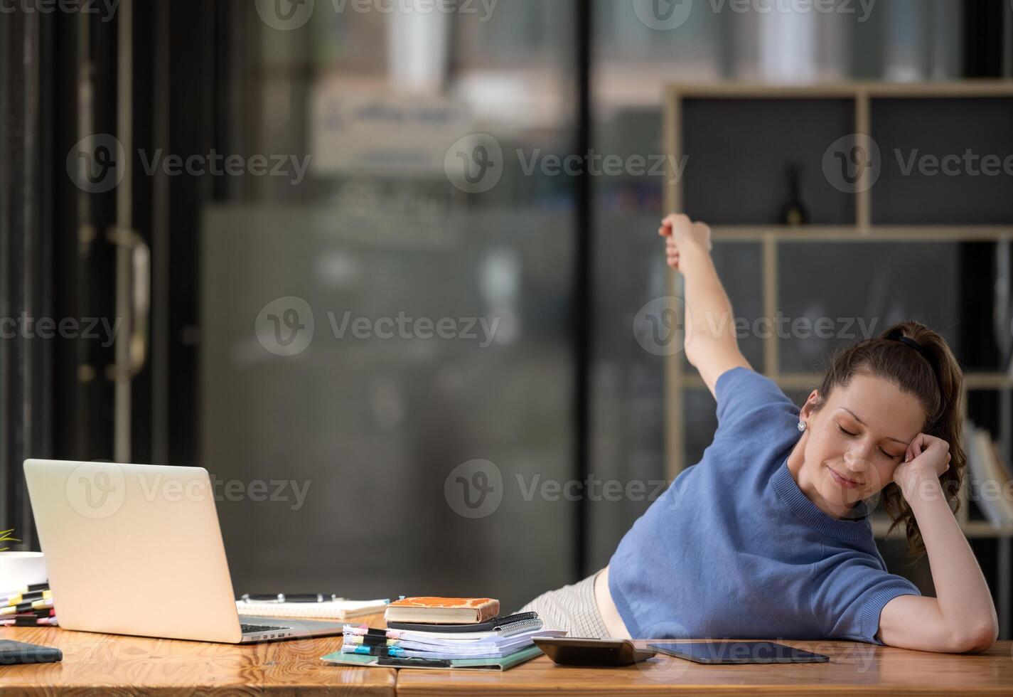 Businesswoman stretching lazy at the desk to relax while working in the office. Feeling stressed and achy from work. photo