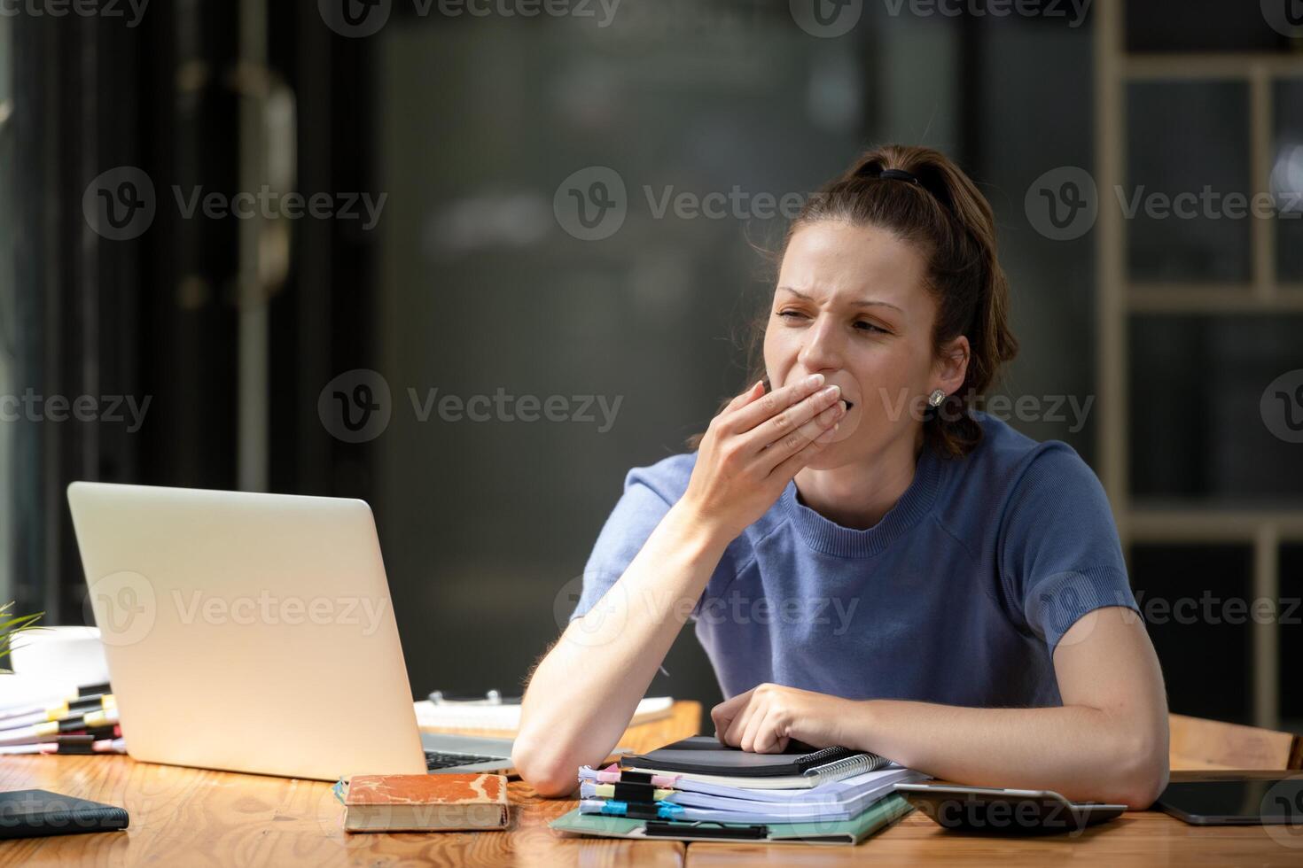businesswoman yawning while working with a laptop computer. Feeling bored and tired. photo