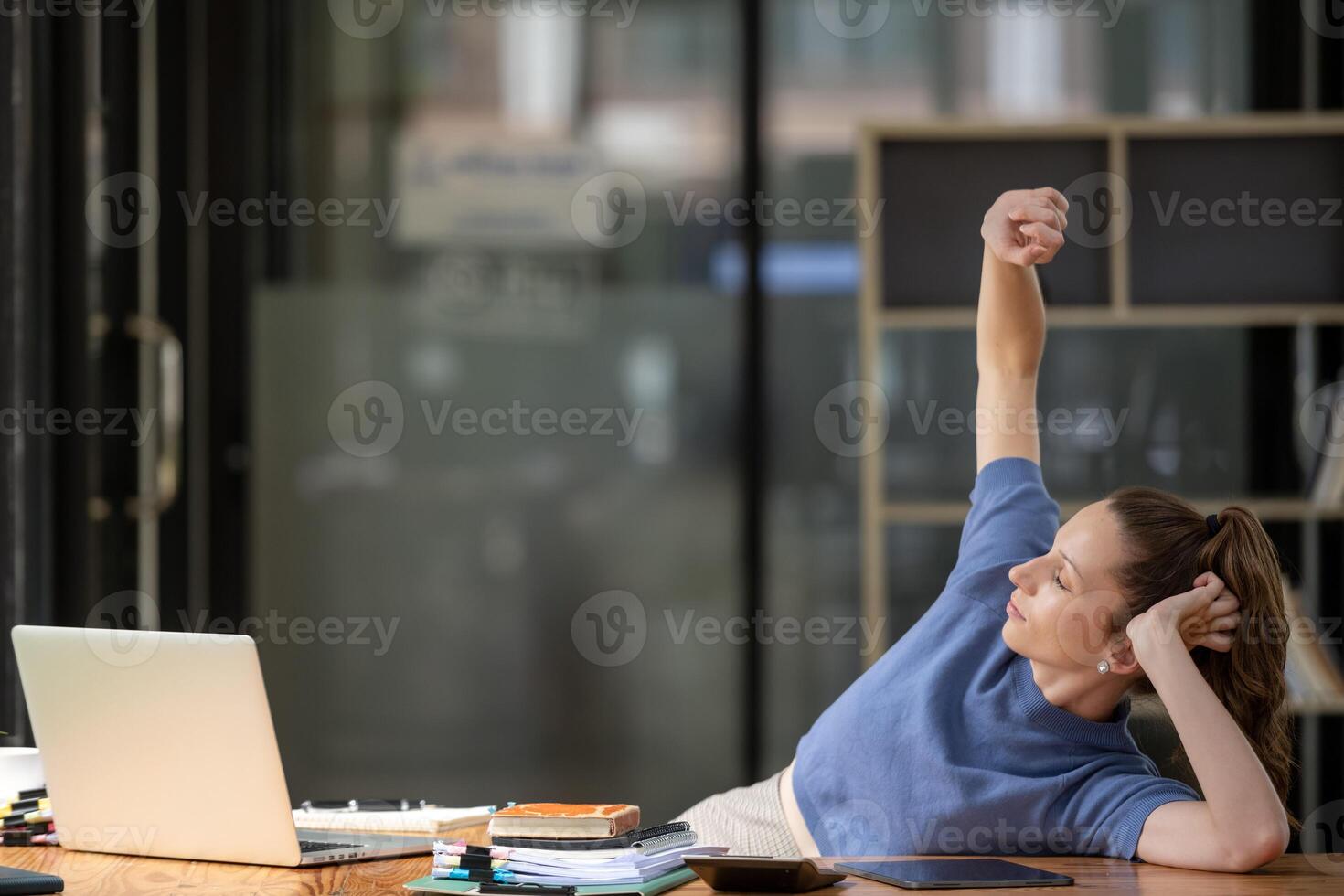 Businesswoman stretching lazy at the desk to relax while working in the office. Feeling stressed and achy from work. photo