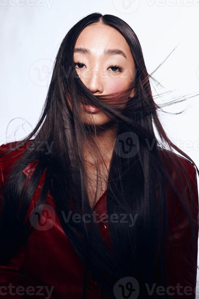Stylish Asian Woman with Long Black Hair and Red Jacket Posing in Front of White Background photo