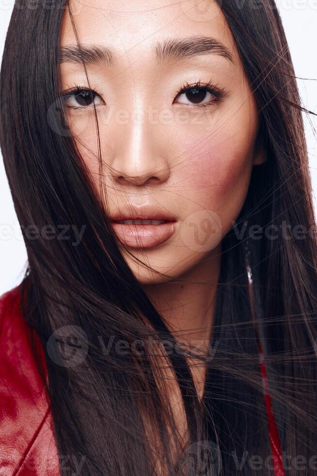 Beautiful Asian woman with long black hair and red jacket posing for the camera outdoors photo