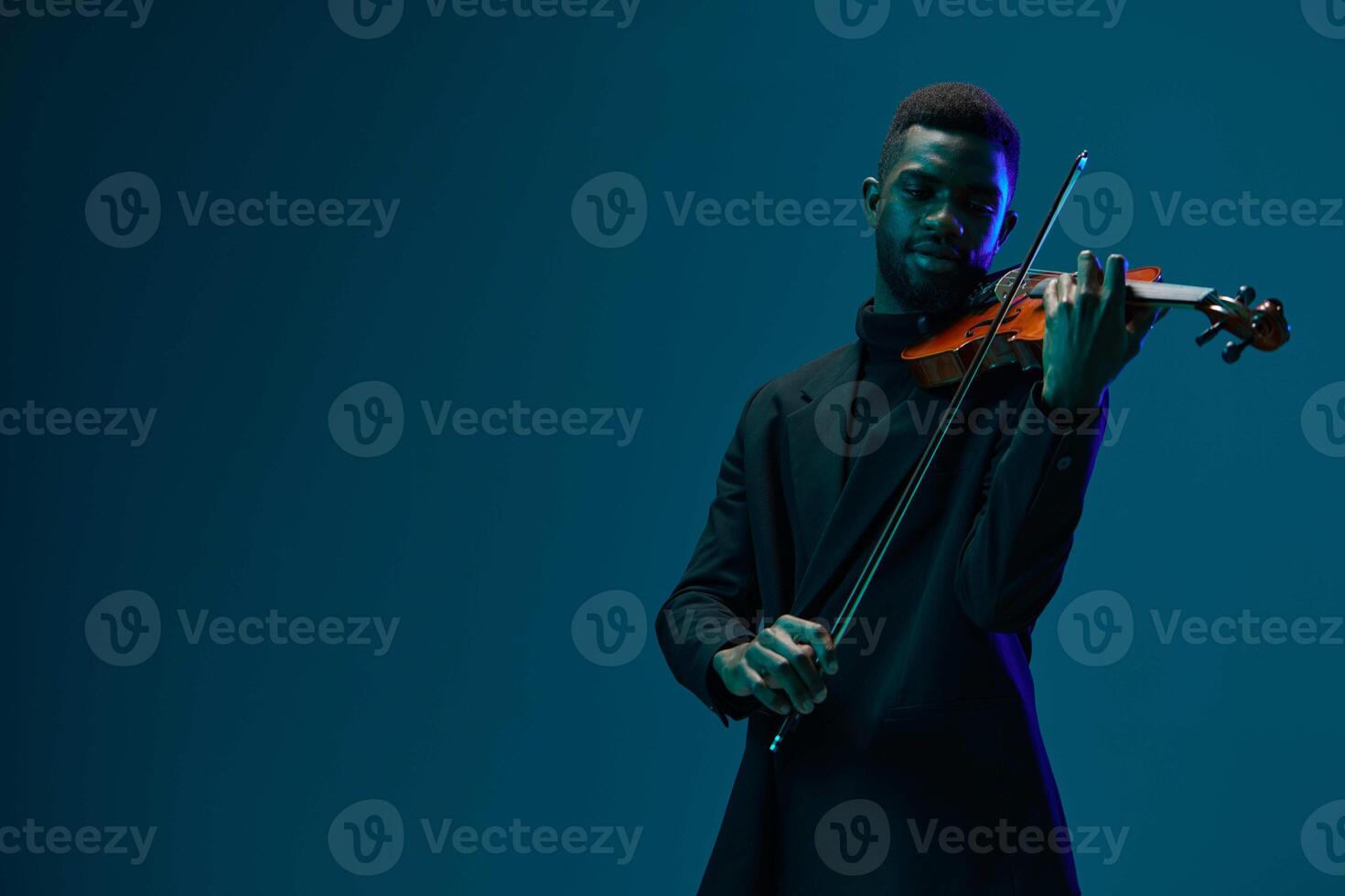 Elegant man playing violin in a suit on dark blue background for classical music concept photo
