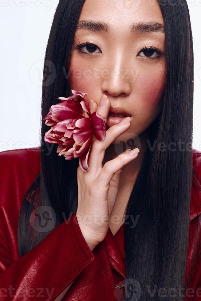 Mysterious woman with long black hair and red jacket holding flower in front of face photo