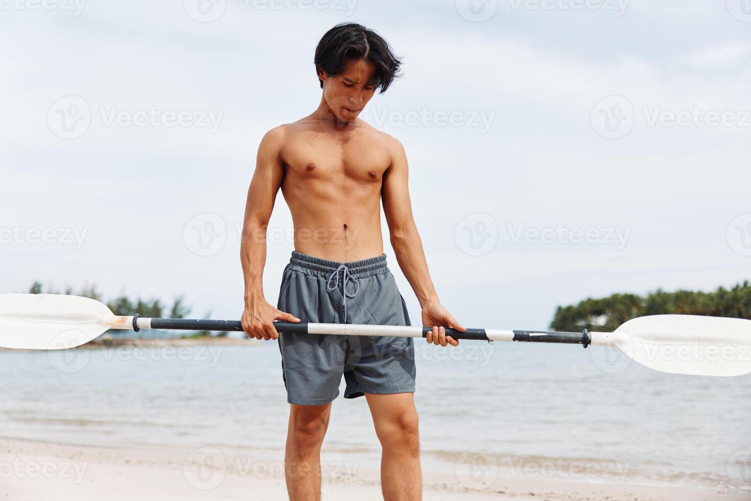 Active Asian Man Enjoying a Fun Summer SUP Adventure on the Beach photo