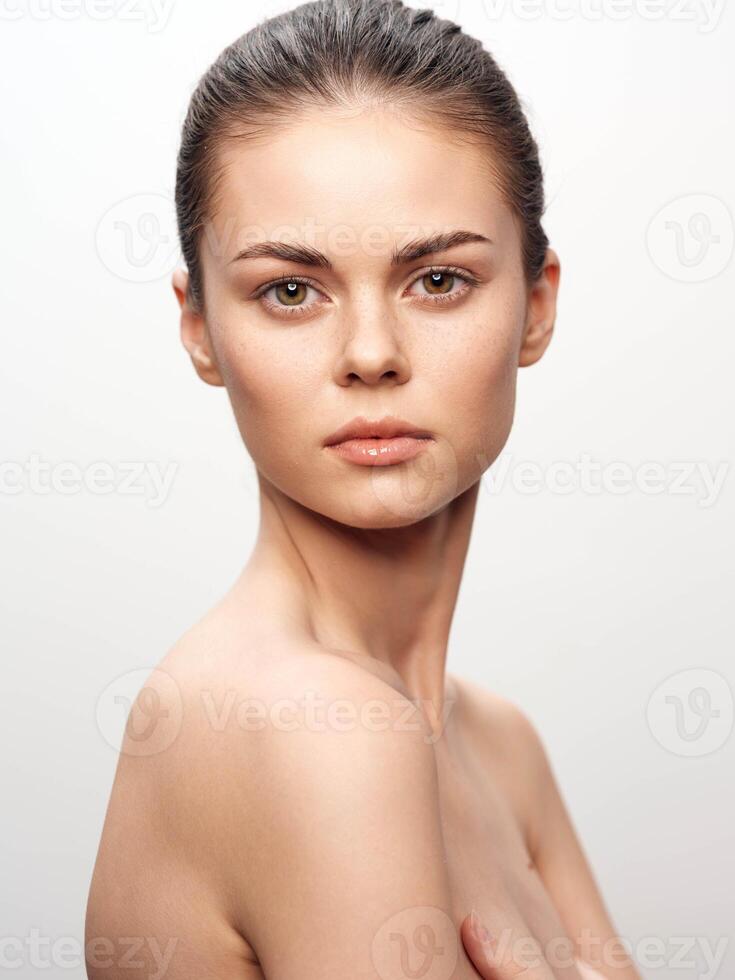 Attractive young woman with bare chest posing elegantly for camera on white background, beauty and photo