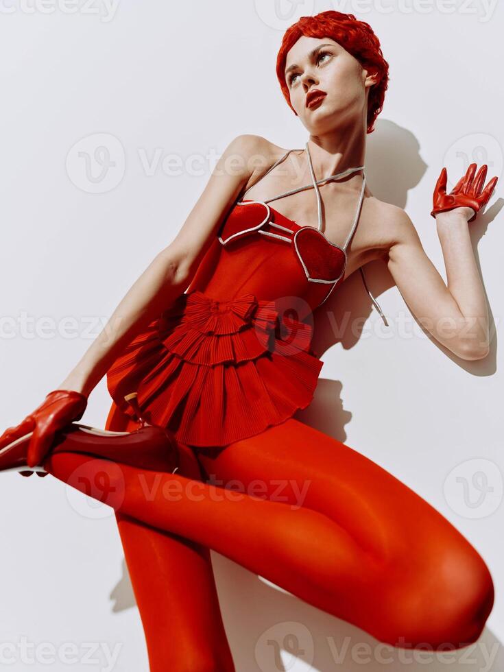 Elegant woman in a red dress lying on the floor with hands on knees in a graceful pose photo