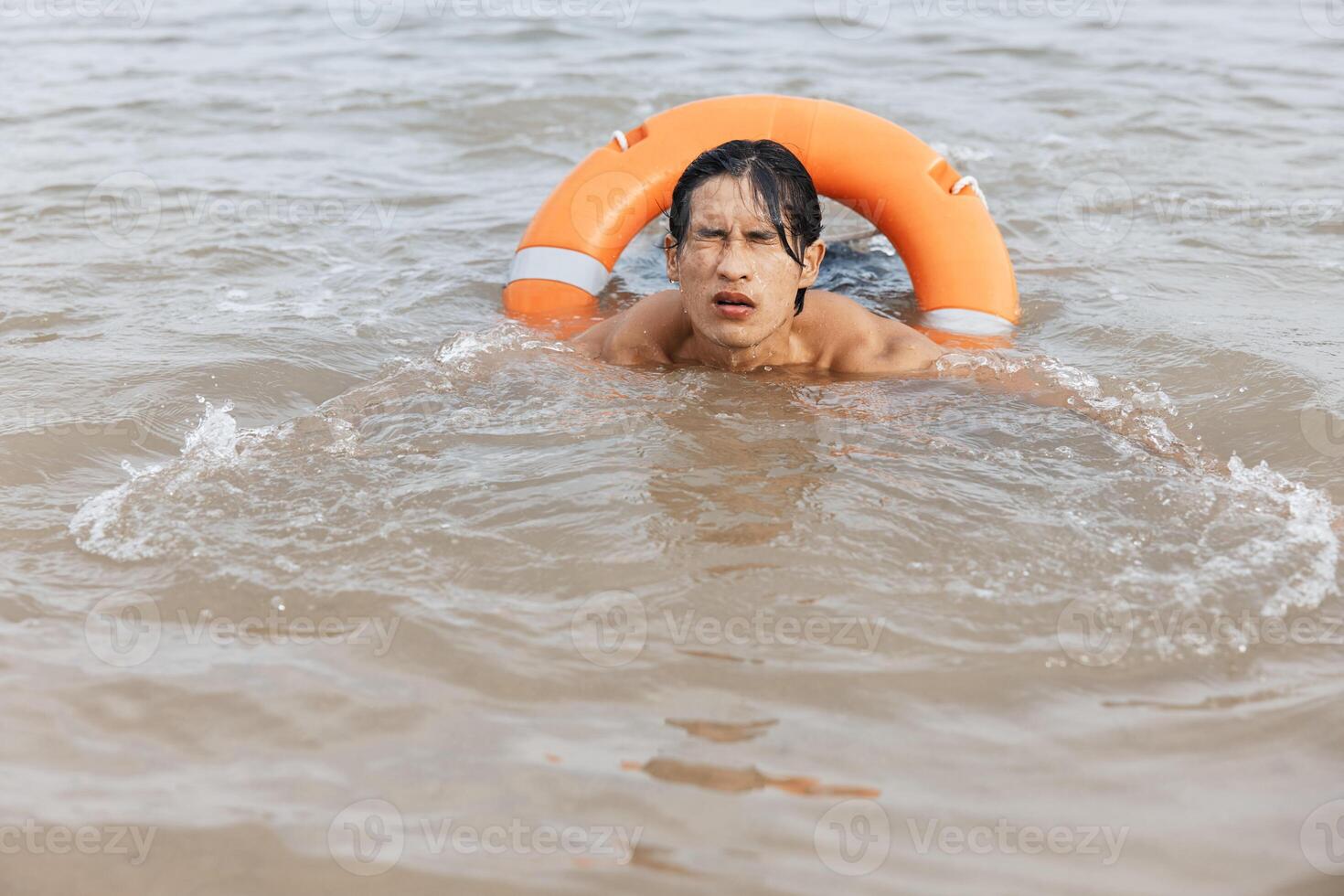 Alert Asian lifeguard using a red lifebuoy in the summer beach. the life saver of the sea. photo