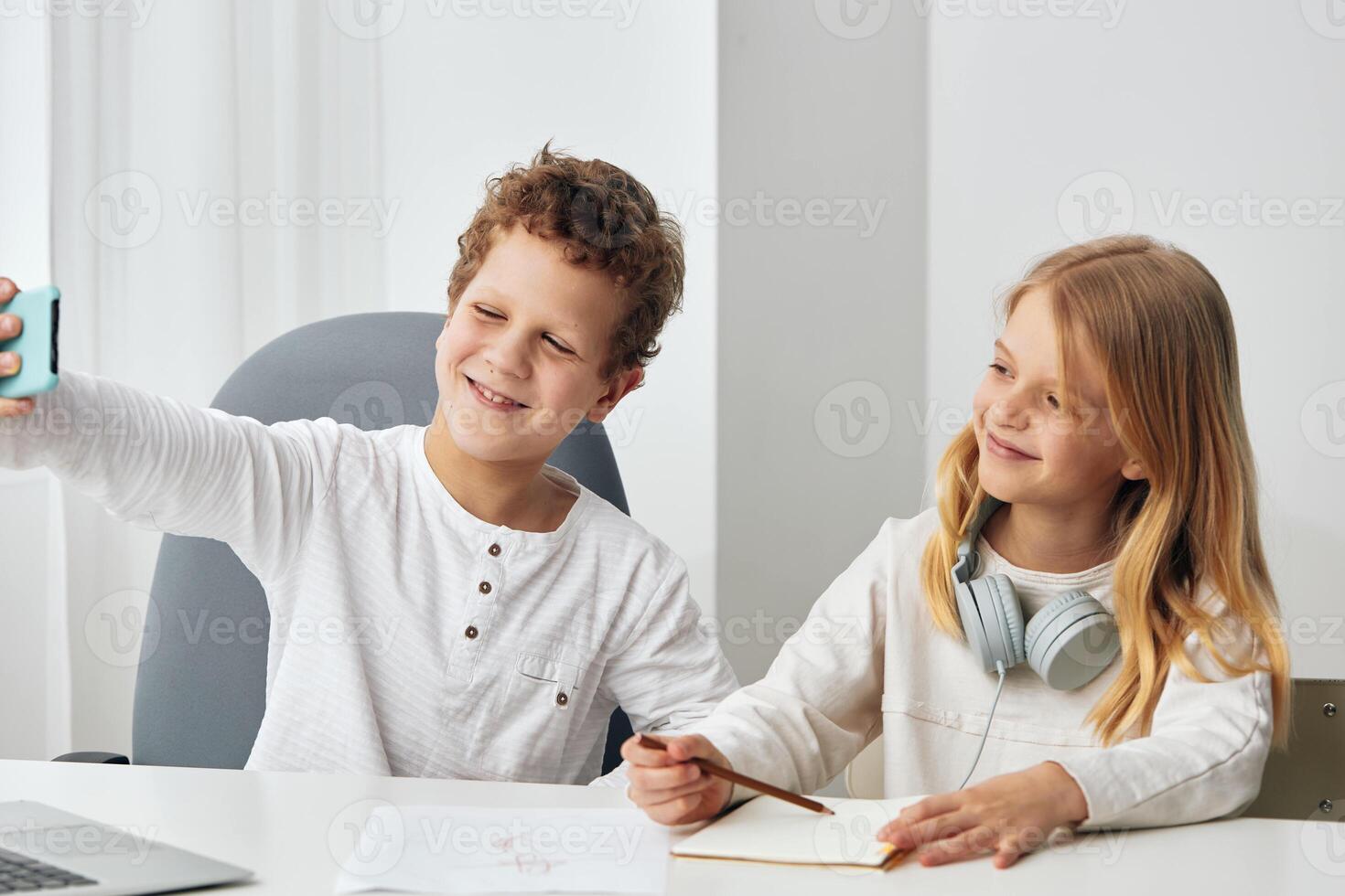 Two Teenage Friends Taking a Selfie on a Smartphone While Sitting and Laughing Together in a Cozy photo