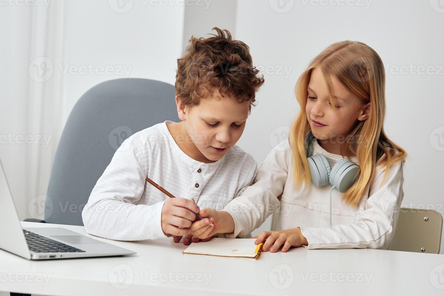 Happy Caucasian siblings studying together at home with their laptops, fully engaged in elearning photo