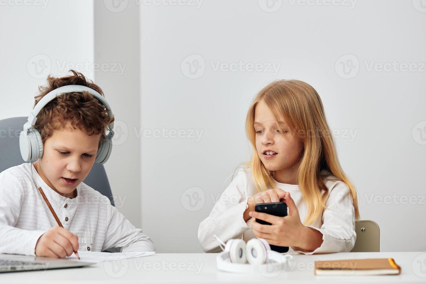 Happy Caucasian children studying at home with their laptops and headphones, enjoying elearning photo
