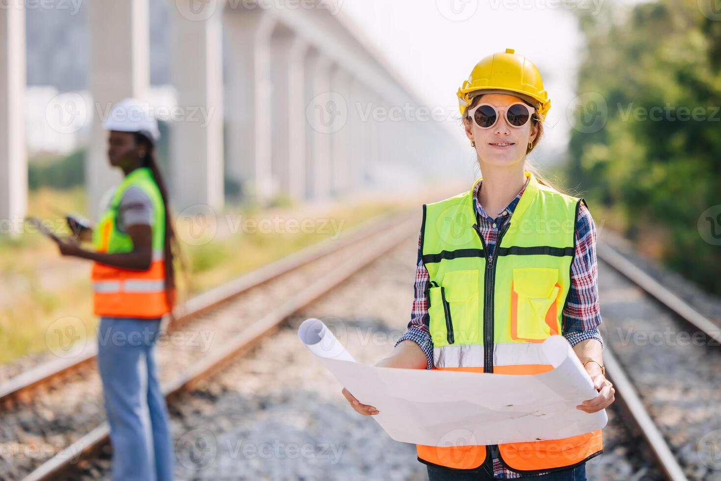 Portrait engineer women on railway tracks construction site with blueprint roll working project manager in suburb transportation line photo