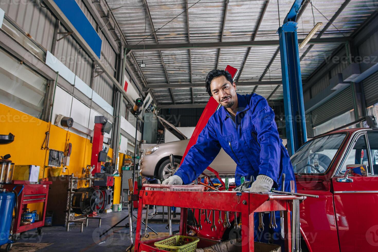Portrait Asian Japanese male mechanic worker portrait in auto service workshop car maintenance center replace fix auto engine part photo