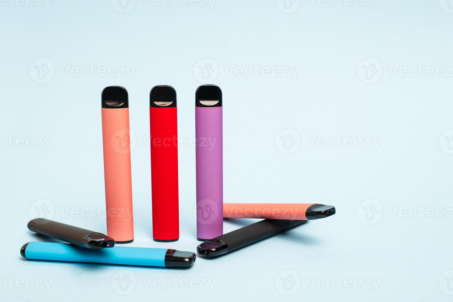 Layout of colorful disposable electronic cigarettes on a light blue background. The concept of modern smoking, vaping and nicotine. photo