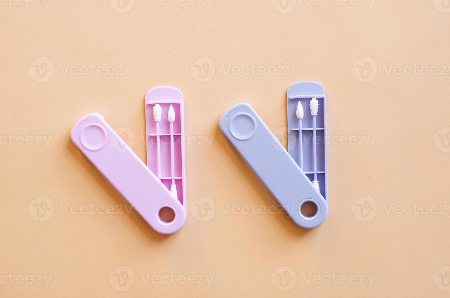 Reusable silicone ear sticks in colored cases with a top view on a beige background. An alternative to disposable cotton swabs. Reduce costs and save money. photo