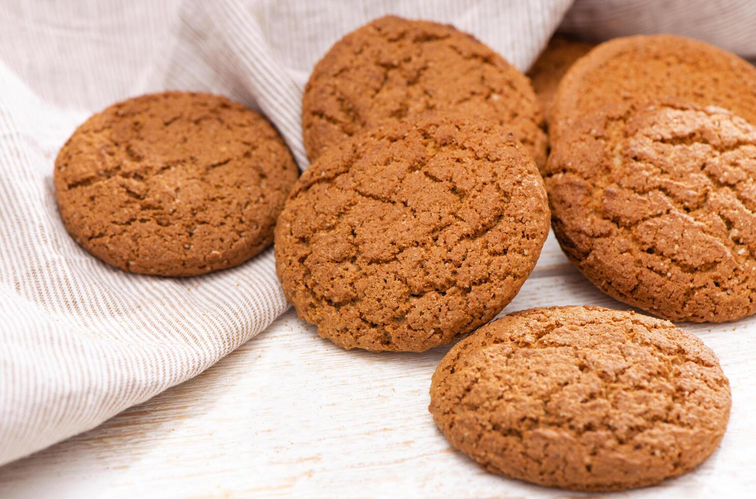 Fresh oatmeal cookies with sugar on a rustic wood table, tea towel. Top view. Homemade baking close up photo