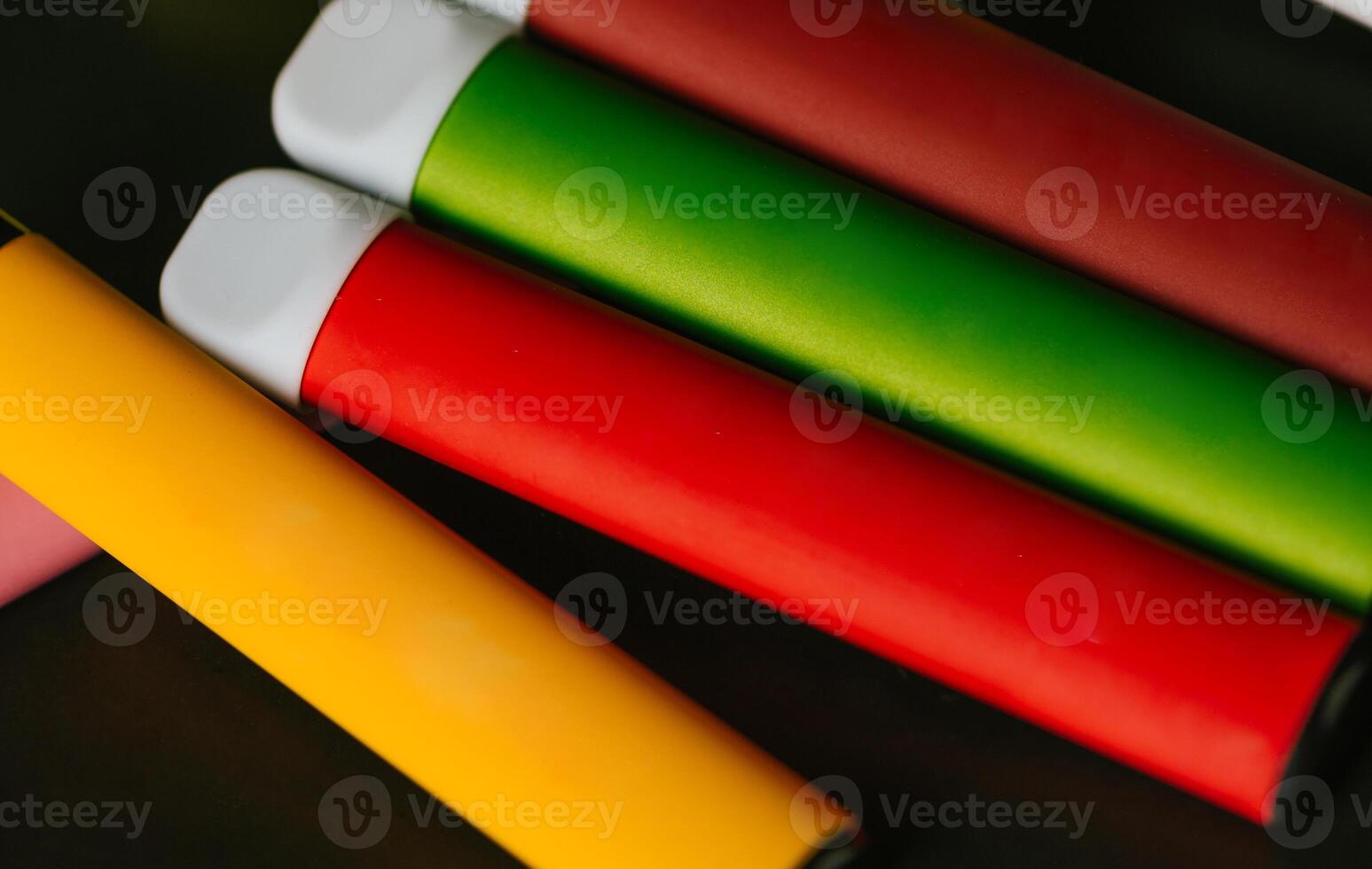 Colorful disposable electronic cigarettes on a black background. The concept of smoking, vaping and nicotine. photo