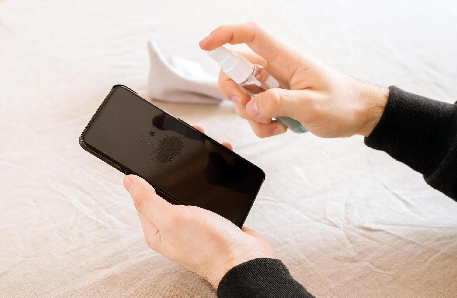 Men's hands is cleaning phone with antiseptic wet wipe. Coronavirus global epidemic. Prevention of coronavirus after visiting public places.Selective focus photo
