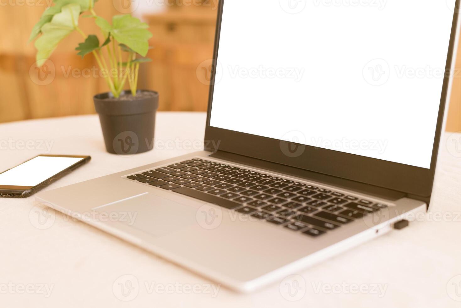 A workplace in a bright kitchen during quarantine. Laptop with place for text. Telework. freelance. flowerpot, phone and cup on the table.Copy space. photo