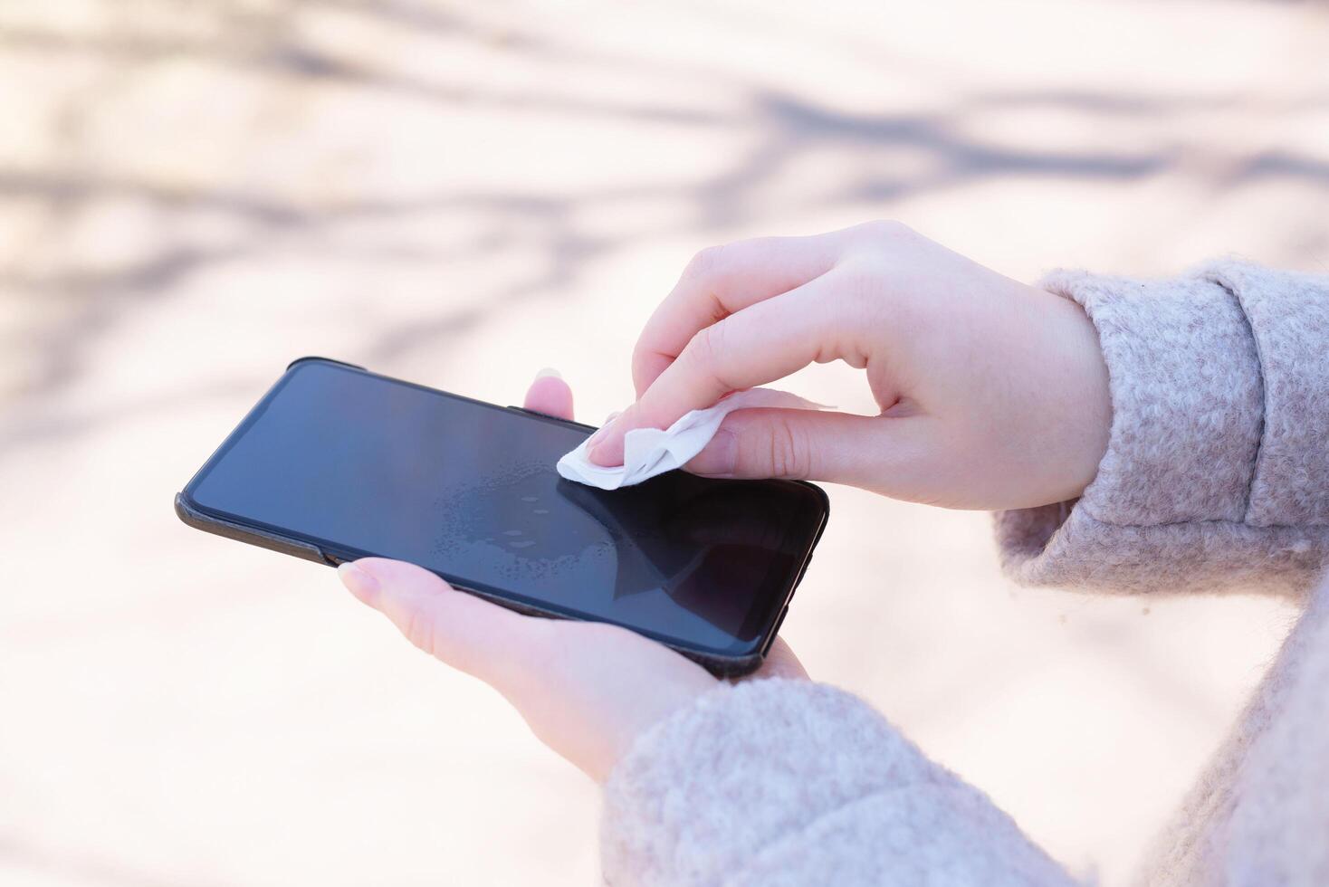 How to clean, sanitize your phone. Cleaning mobile phone to eliminate germs, coronavirus Covid-19. Man hands cleaning smartphone by disinfectant napkin. Hygiene concept. photo