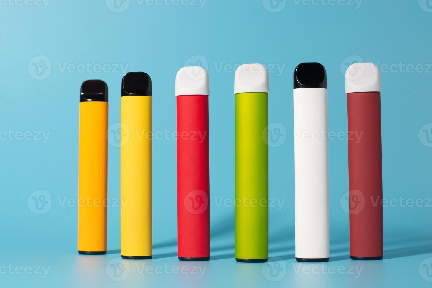 Set of colorful disposable electronic cigarettes with shadows on a blue background. The concept of modern smoking, vaping and nicotine. Top view photo