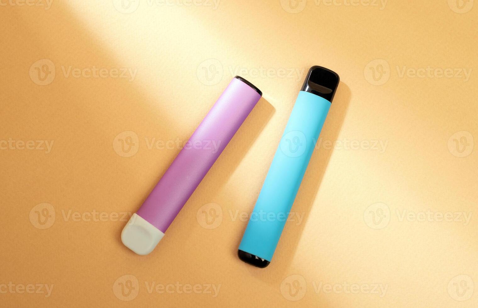 disposable electronic cigarettes with shadow on a beige background with copy space. The concept of modern smoking, vaping and nicotine. photo