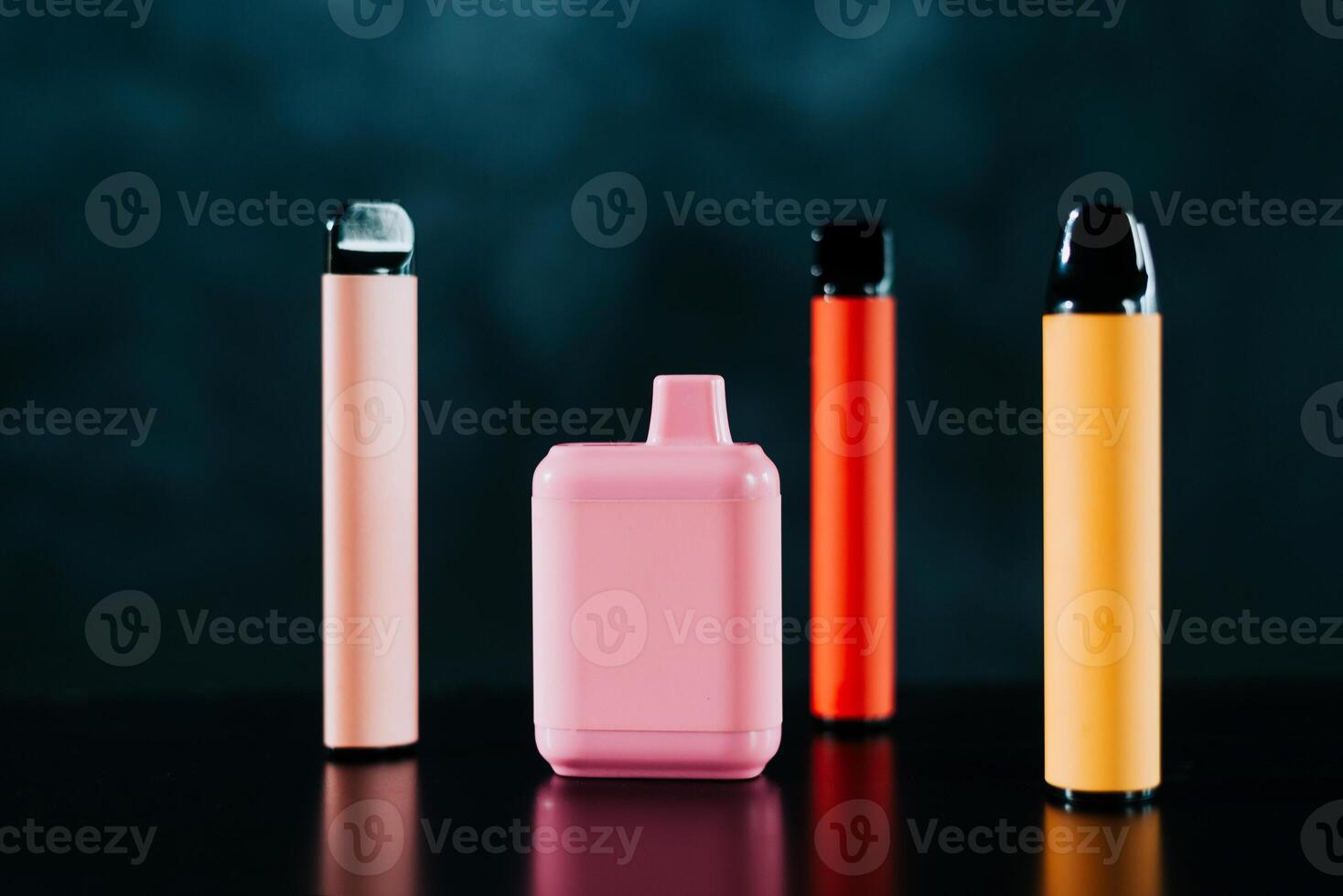 A set of colorful disposable electronic cigarettes of different shapes on a black background with smoke. Concept of modern smoking, vaping and nicotine. photo