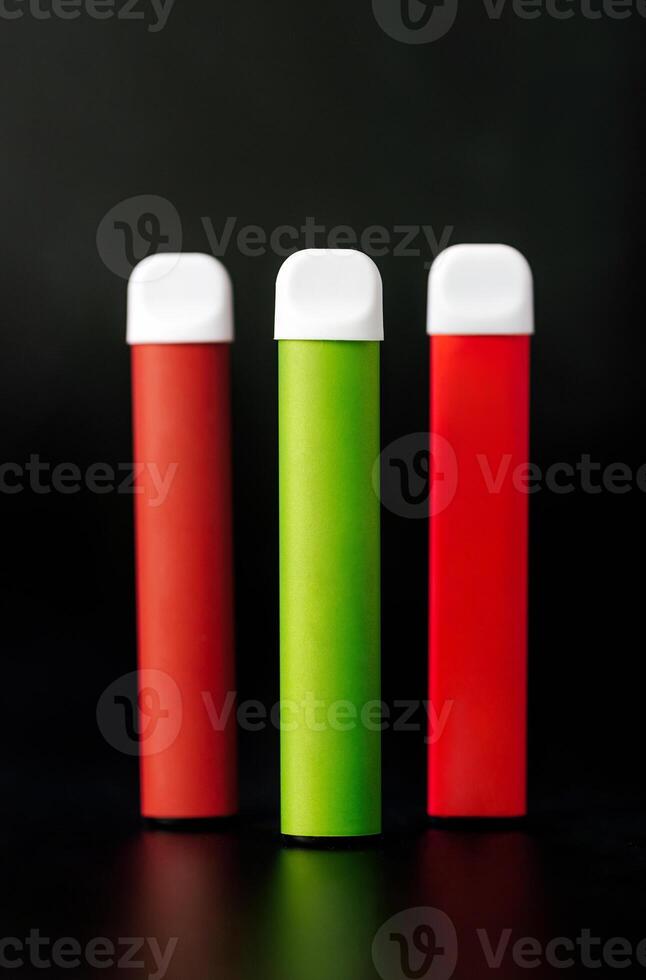 Colorful disposable electronic cigarettes on a black background. The concept of modern smoking, vaping and nicotine. photo