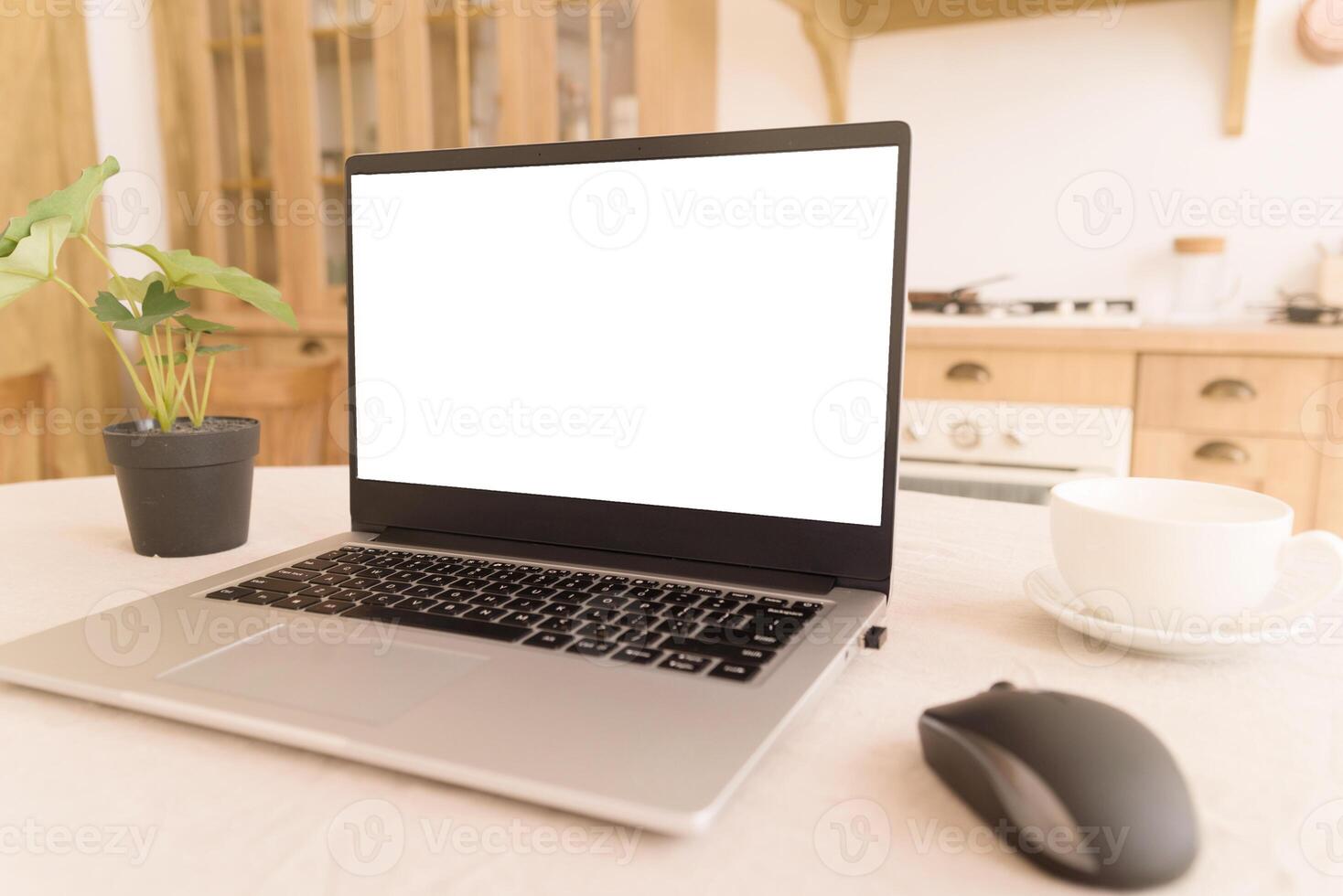 A workplace in a bright kitchen during quarantine. Notebook with place for text. Telework. freelance. flowerpot, mouse and cup on the table. copy space photo