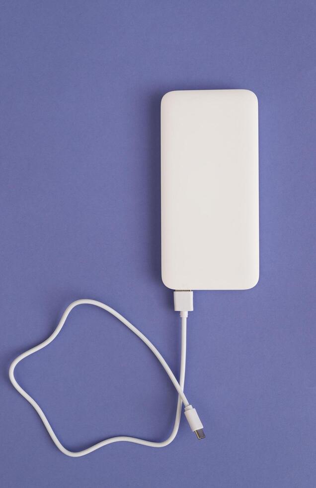 White Power Bank with USB Cable on purple Background Top View photo
