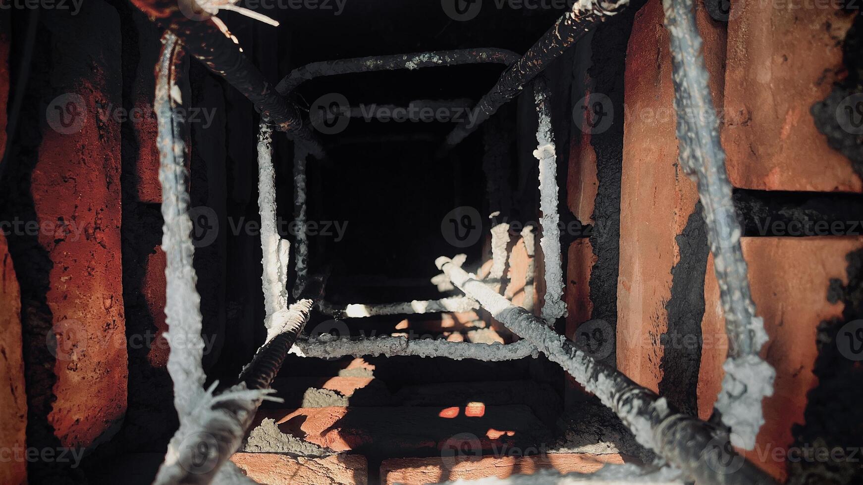 Closer view of a dark hole between steel bars and bricks photo