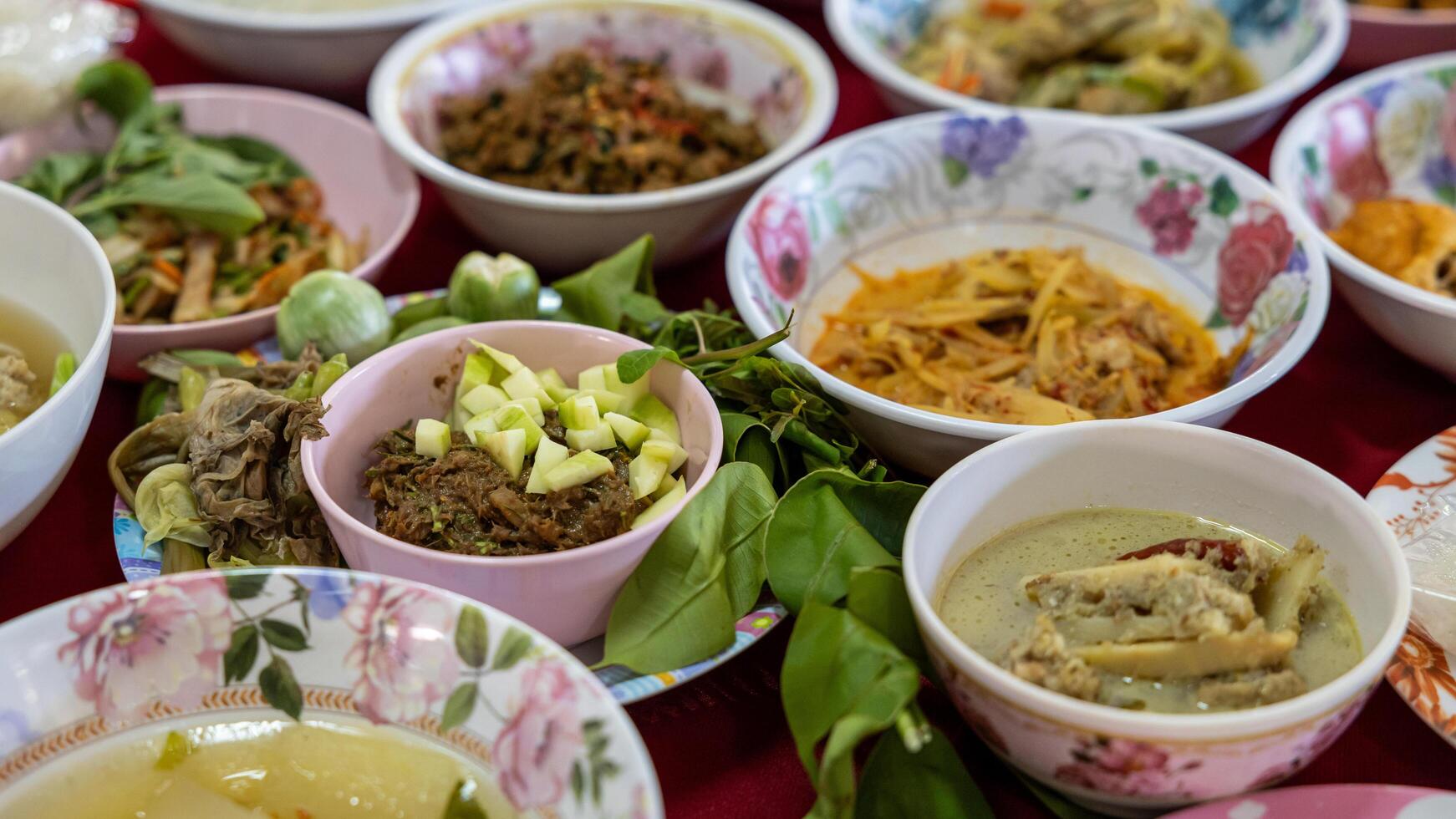 Close-up view of sticky rice, curry, laab, stir-fry and many other dishes packed in bowls. photo