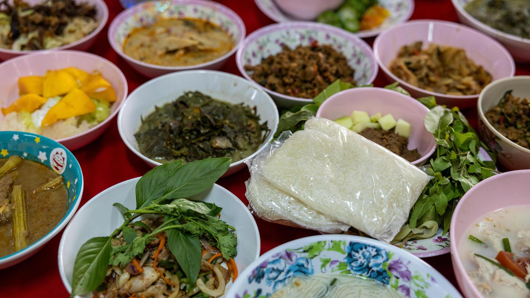 Close-up view of sticky rice, curry, laab, stir-fry and many other dishes packed in bowls. photo