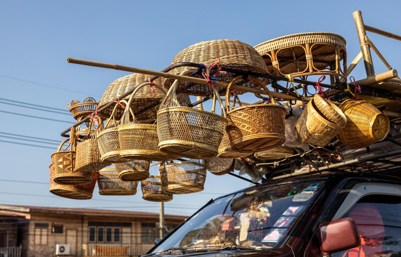 A low-level view of woven bamboo baskets and other things hanging for sale. photo