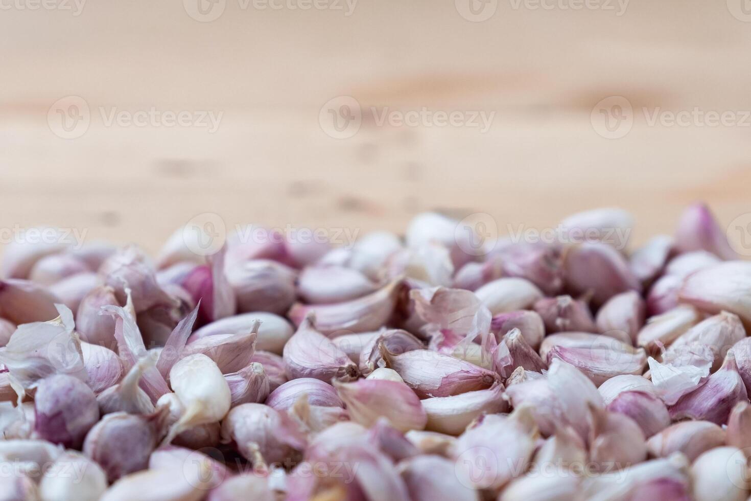 Heap of fresh garlic cloves with peel on wooden table photo