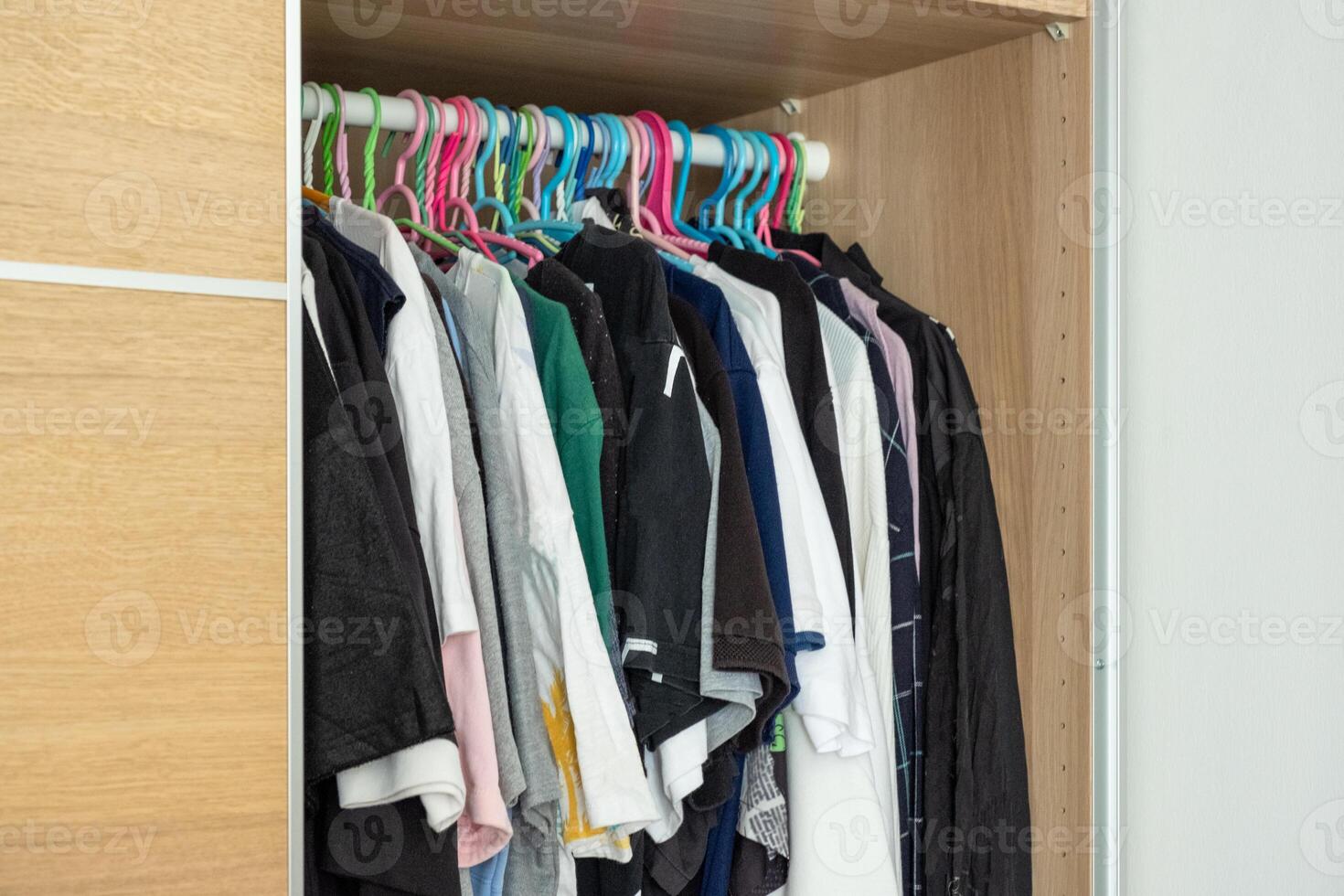 Many shirt and casual men clothes hanging rail in closet photo