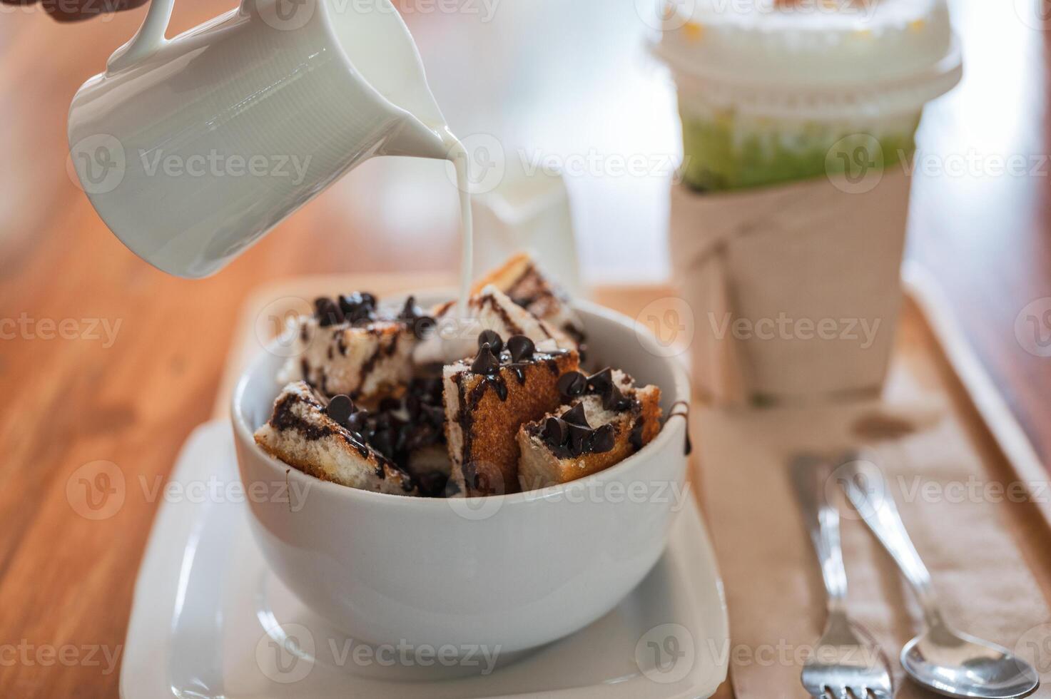 Pouring fresh milk on banana chocolate chip bread with ice honey tea photo