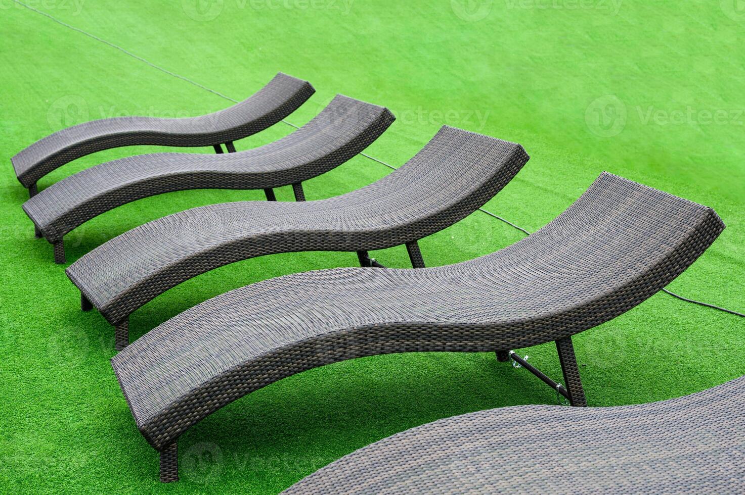 Modern black loungers on artificial lawn on poolside photo