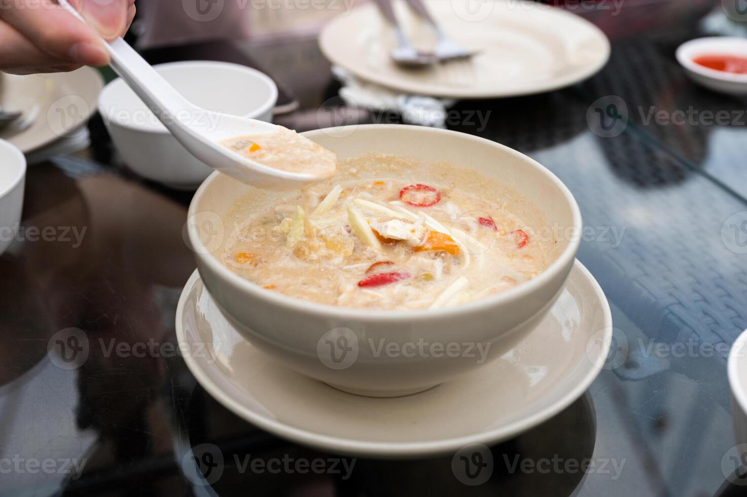 Hand scoop chili paste simmer crab with coconut milk and vegetables in bowl photo