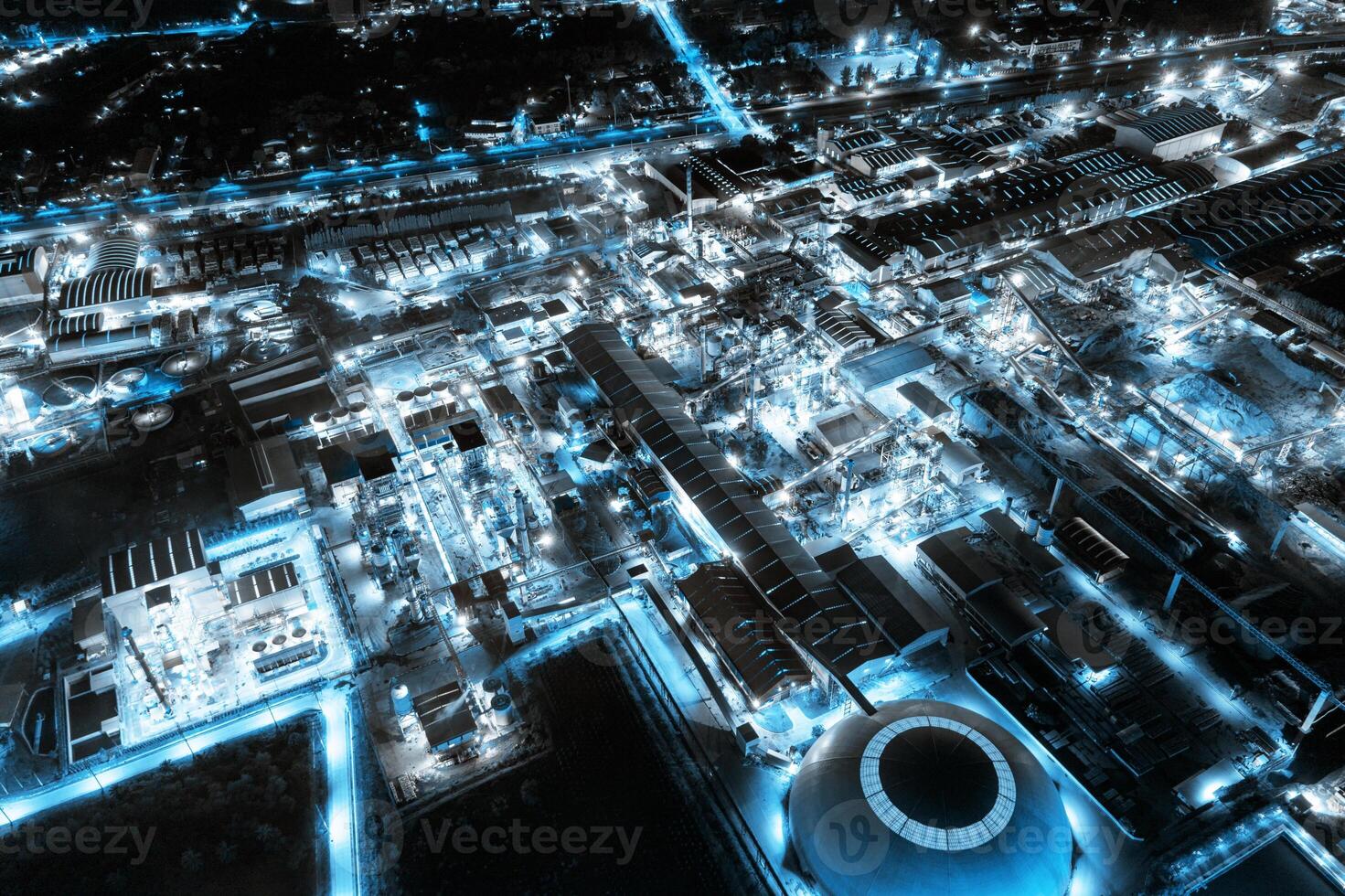 Blue light industrial factory with chemical refinery and building material glowing light at night photo