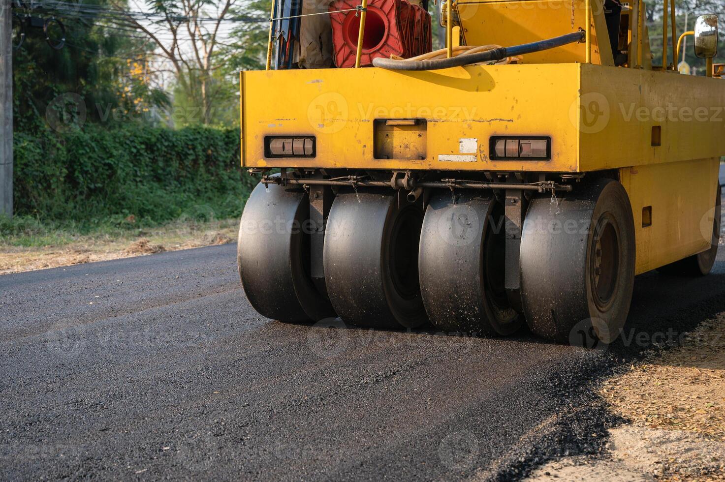 Heavy vibration yellow steamroller or soil compactor working on hot-mix asphalt pavement road photo