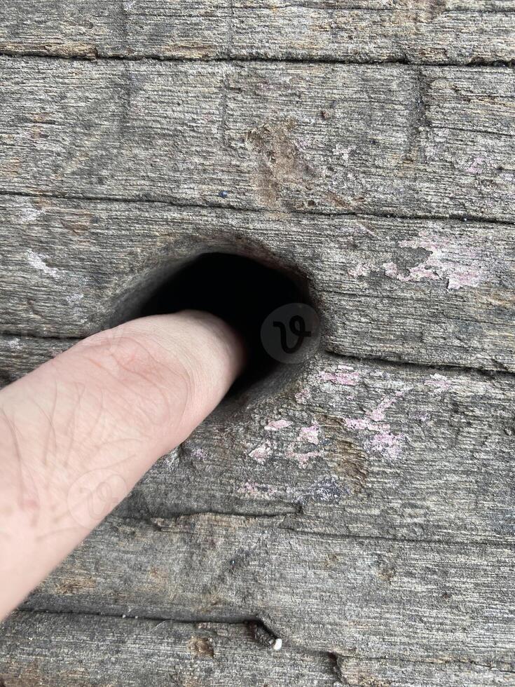 hand with a hole in a wooden surface photo