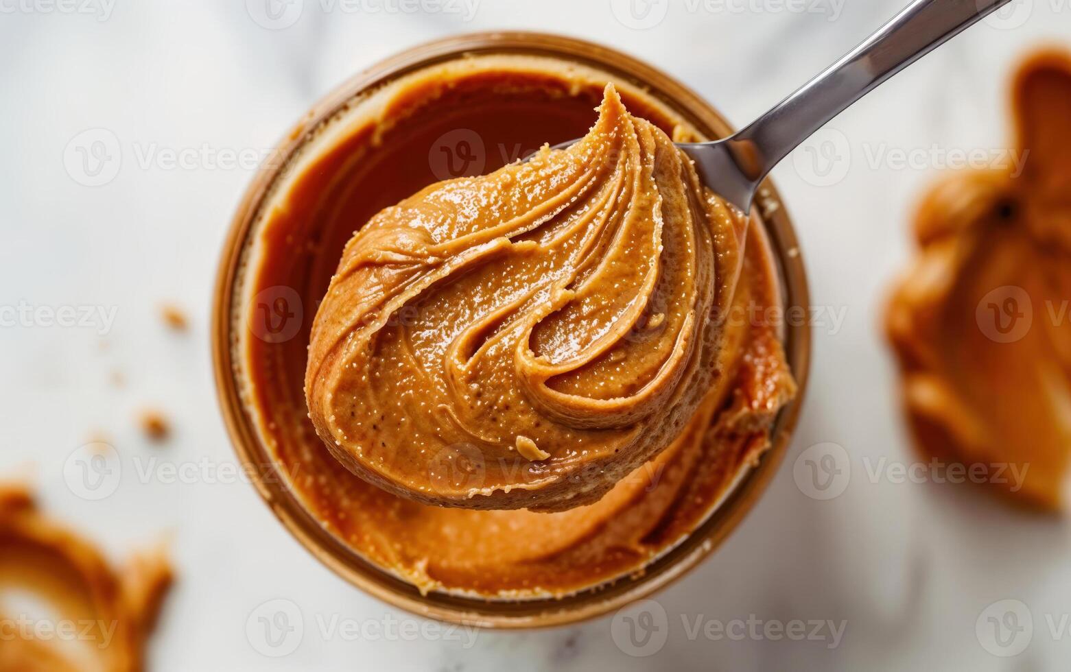 Closeup of smooth peanut butter texture in a glass jar with a spoon photo