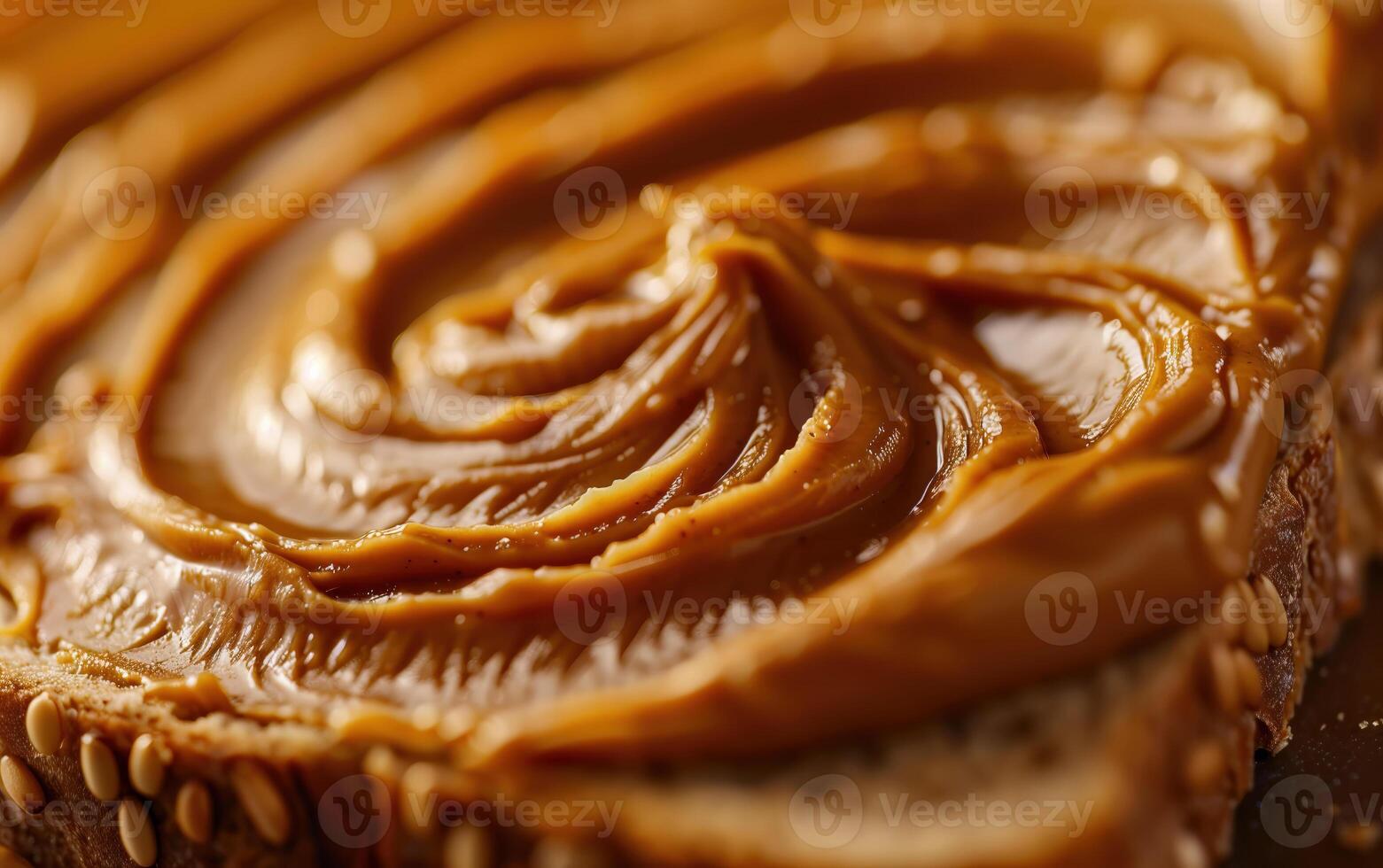 Closeup of smooth peanut butter spread on a slice of toast with sesame seeds photo