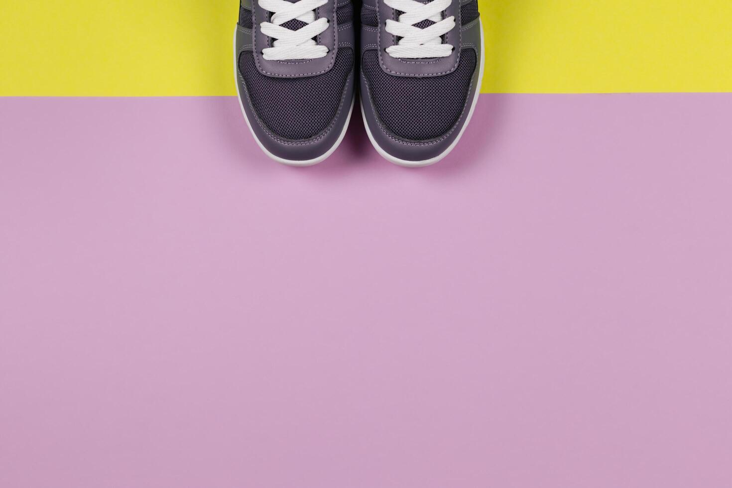 Grey sneakers on the yellow and violet background. Concept for healthy lifestyle and everyday training. photo