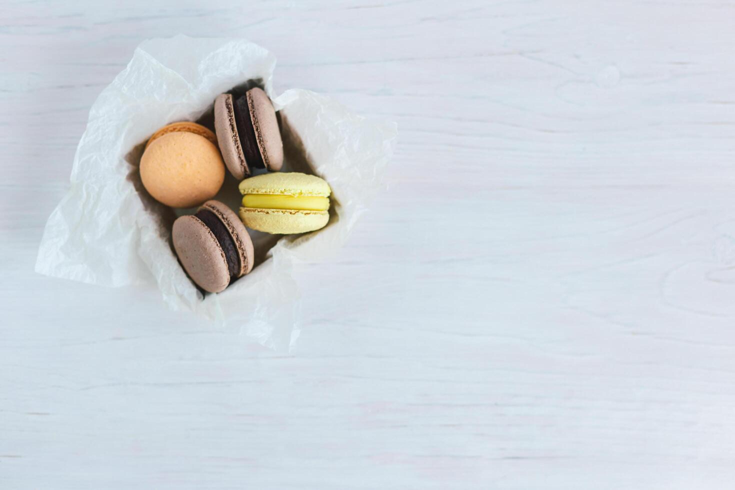 Tasty french macarons in gift box on a white wooden table. Pastel colors. photo